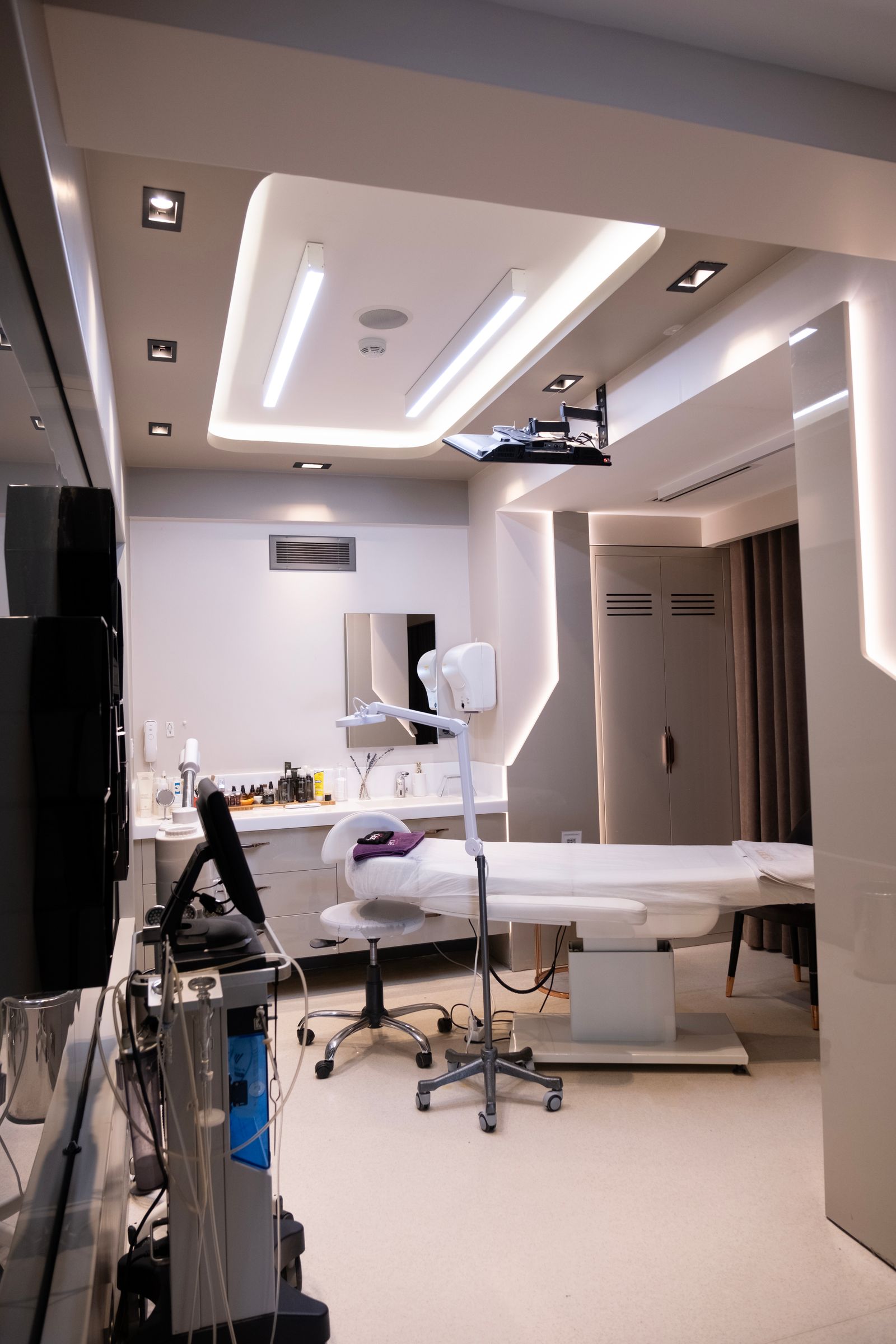 A modern, clean laser treatment room with calibrated overhead lighting and medical-grade equipment